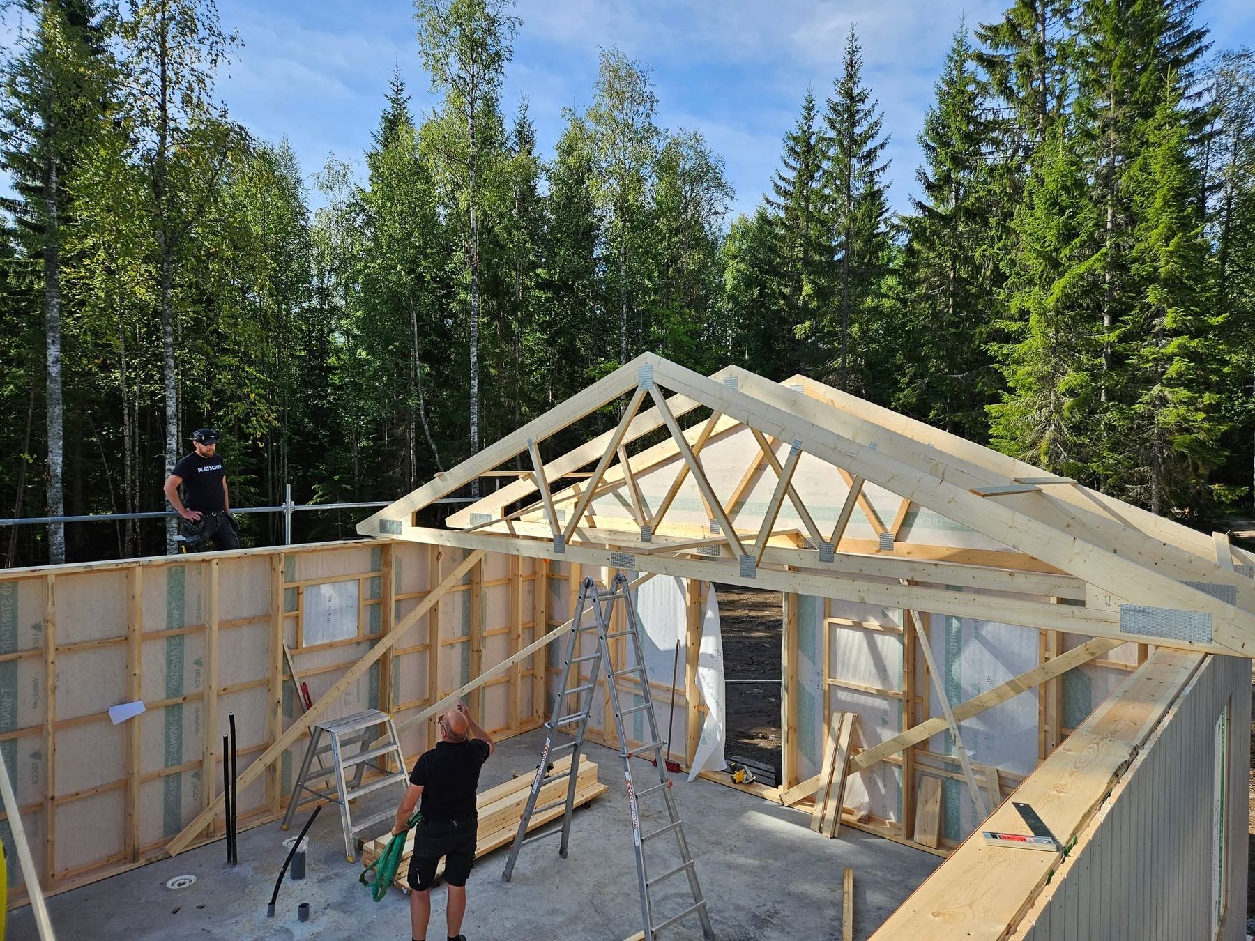 Takstolar reses på ett nybygge i skogen