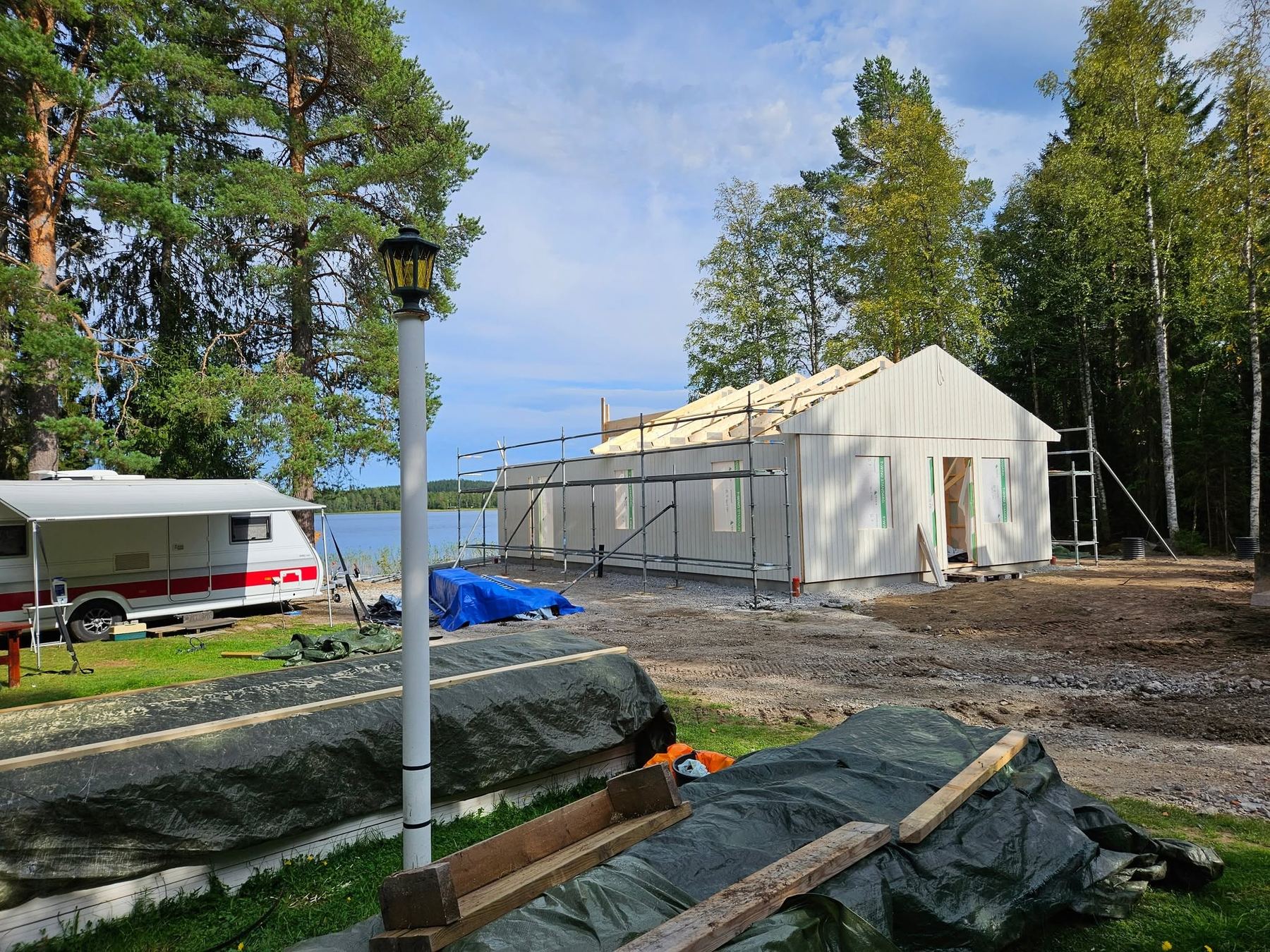 Nybygge vid sjön med stomme, takstolar och byggställning