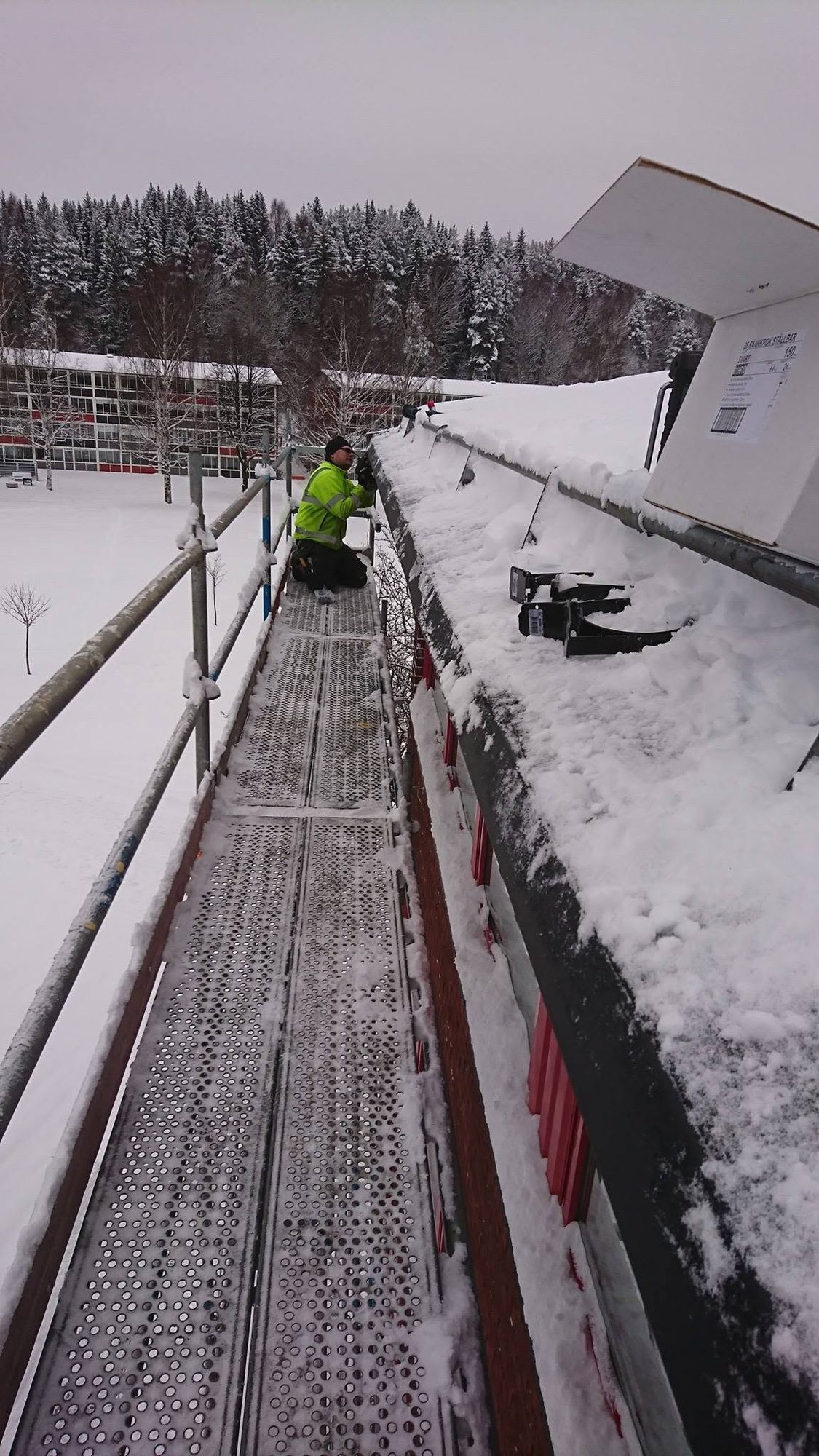 Plåtslagare på byggställningen vid takfoten en snöig vinterdag